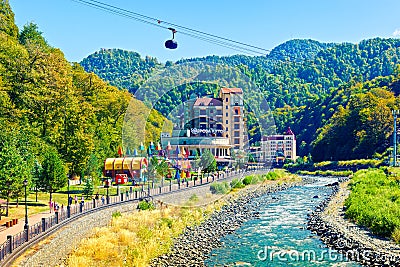 People walk along the bank of river Mzymta in famous resort town Roza Khutor Editorial Stock Photo