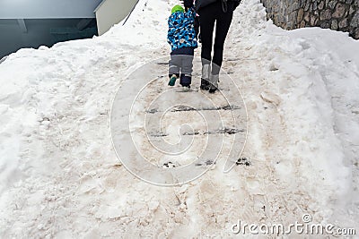 People walk by concrete stone staircase covered dirty deep slippery snow after blizzard snowstorm snowfall at city Stock Photo