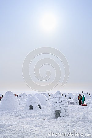 People walk on snow-covered lake among the igloos built for the contest, the traditional shelter of the northern peoples from Stock Photo