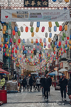 People walk under rainbow coloured lanterns on a street in Chinatown, London, UK Editorial Stock Photo