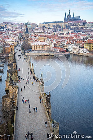 People are walking on Charles bridge, whose rooftops are covered by snow, Prague in the winter Editorial Stock Photo