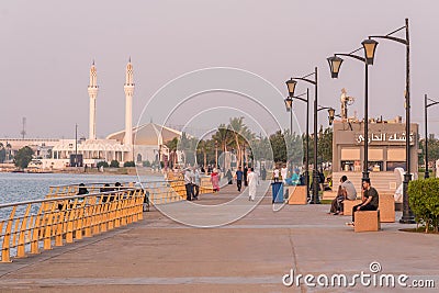 People walking down the Jeddah corniche in Saudi Arabia. Hassan Enany Mosque is seen on the background. Editorial Stock Photo