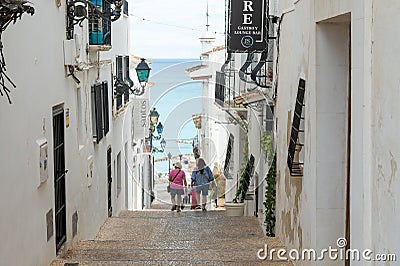 People walking down a steep path between two buildings with sea in the background in Altea, Spain. Editorial Stock Photo