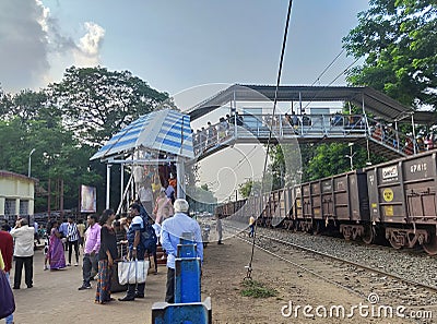 People walking through foot over bridge at Jhargram Railway station, West Bengal, India. Wide view of train Editorial Stock Photo