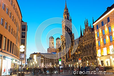 People walking at Marienplatz square and Munich city hall in night in Munich, Germany. Cafes, bars, shops and restaurants. Motion Editorial Stock Photo