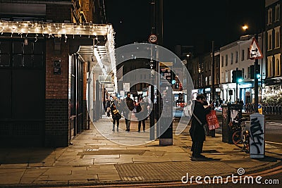 People walking past the shops and cafes in Spitalfields Market, London, UK, in the evening Editorial Stock Photo