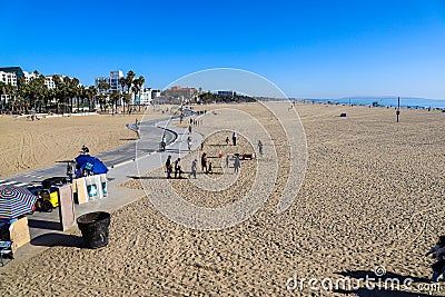 People walking, running and riding bikes along a smooth winding footpath at the beach with silky brown sand, hotels Editorial Stock Photo
