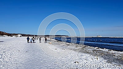 People are walking on a snow-covered beach in Sopot on a beautiful sunny day Editorial Stock Photo