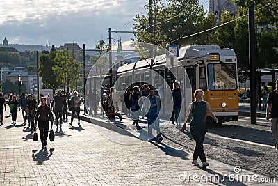 People walking on the street in front of a yellow streetcar Editorial Stock Photo
