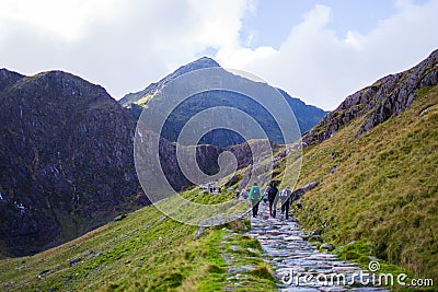 People walking to the summit of a mountain through a pathway surrounded by beautiful landscapes in Snowdonia, Wales Editorial Stock Photo