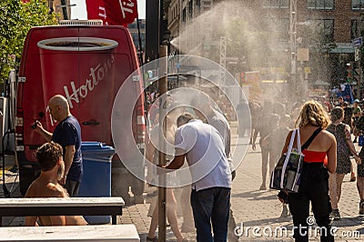 People walking under misting system to cool off during heatwave Editorial Stock Photo