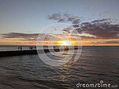 People watch Dramatic Sunset jetty in the water off Waikiki beach Editorial Stock Photo