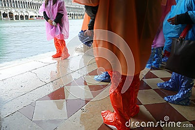 people with waterproof gaiters to protect their footwear during high tide on the island of Venice Italy Stock Photo