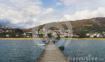 People in wood pier over Plav lake. Fisherman small coast town with ferryboats in Montenegro Stock Photo