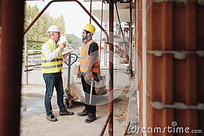 Portrait Of Happy Construction Site Supervisor Talking To Manual Worker Stock Photo