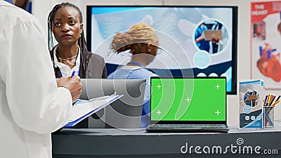 People working with greenscreen display on laptop in facility lobby Stock Photo