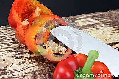 A pepper cut into two halves with a sharp knife. Knife lay next to cuttable pepper Stock Photo