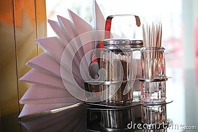 Pepper and salt shaker, toothpicks and napkins on the table in the cafe in front of the window in the evening. Stock Photo