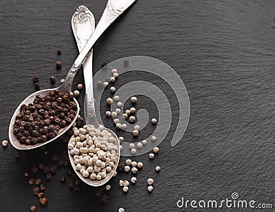 Peppercorns in rustic silver spoons on dark background Stock Photo