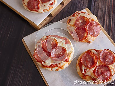 Pepperoni and Mozzarella Cheese Mini Pizzas served on Wooden Plates over White Food Paper Stock Photo