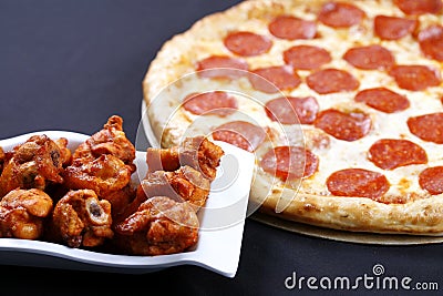 Pepperoni pizza with chicken wings Stock Photo