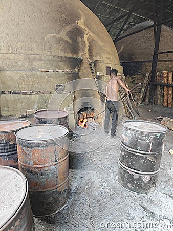 Scene of the worker putting mangrove logs into the charcoal kiln to produce pure carbon Editorial Stock Photo