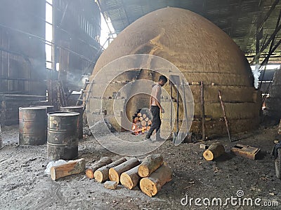 Scene of the worker putting mangrove logs into the charcoal kiln to produce pure carbon Editorial Stock Photo