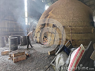 Scene of the worker putting mangrove logs into the charcoal kiln to produce pure carbon Editorial Stock Photo