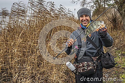 Perch fishing. Happy smiling fisherman hold fish and tackle. Success fishing at autumn lake Stock Photo