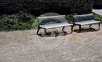 Perennial bed mulched with gray gravel in front of a limestone stone wall in a square with benches with wood paneling, beige path Stock Photo
