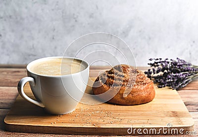 Perfect breakfast of homemade cinnamon bun and coffee on wooden table decorated with lavender. Rustic style. Stock Photo