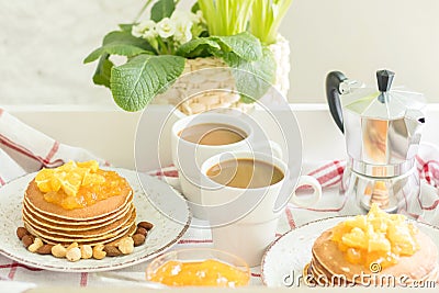 Perfect breakfast for 2. Tray with pancakes with orange jam and nuts on vintage plates and 2 white coffee cups Stock Photo