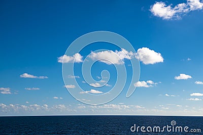 Perfect clouds in blue sky, fluffy clouds in bright sky over ocean. Dark blue calm sea water. Stock Photo