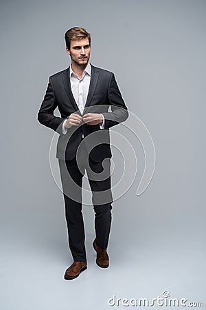 Perfect man. Full length of handsome young man in full suit buttoning his jacket and looking at camera while standing Stock Photo