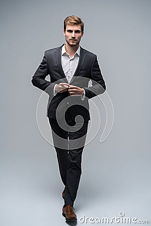 Perfect man. Full length of handsome young man in full suit buttoning his jacket and looking at camera while standing Stock Photo