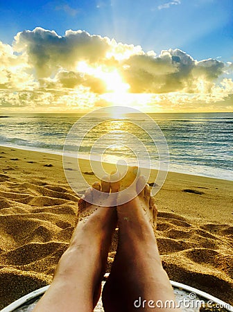 Perfect Paradise Feet up relaxing watching a glorious golden sunrise over the beach in Kauai Hawaii Stock Photo