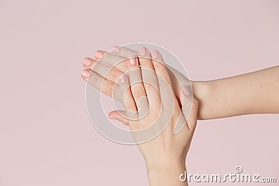 Perfect pink manicure on nails. Beautiful woman hand with clean skin over pink backdrop. Stock Photo