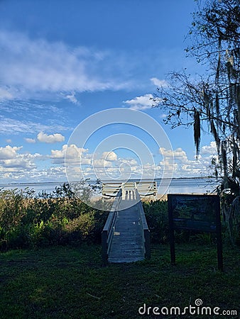 Perfect sunny Florida lake marsh grass clouds fishing pier Stock Photo