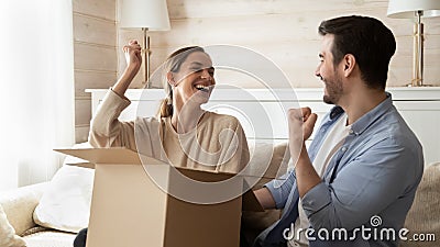 Overjoyed millennial married couple receiving big cardboard package by mail Stock Photo