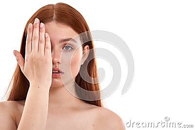 Perfect woman. Portrait of a young sensual red-haired girl with freckles on face covering half face with hand and Stock Photo