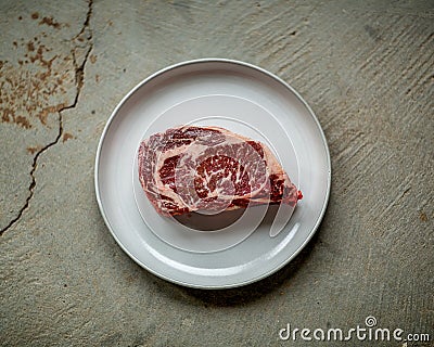 Perfectly Marbled Raw Filet of Steak on a Plate and Grunge Concrete Table Stock Photo