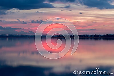 Perfectly symmetric reflection of sunset on a lake, with warm Stock Photo