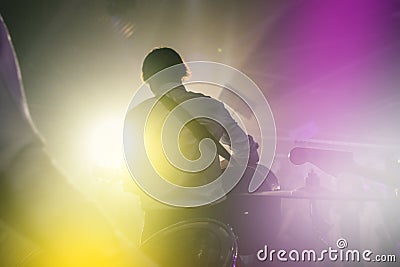 Performance of a rock band at a concert or party. Silhouettes of musicians, guitarist and drummer. People dance to the music, the Stock Photo