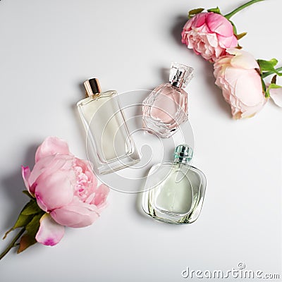 Perfume bottles with flowers on light background. Perfumery, cosmetics, fragrance collection. Flat lay Stock Photo