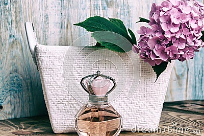 Perfumes and hydrangea in a white basket on blue wooden background Stock Photo