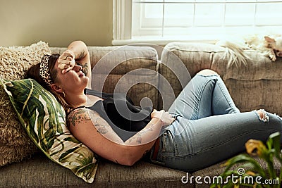 Period pain, menstruation and a woman on a sofa in the living room of her home suffering from cramps. Stomach, digestion Stock Photo