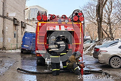Firefighters of the Ministry for Emergency Situations of the Russian Federation use a fire hydrant next to the fire truck Editorial Stock Photo