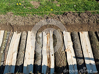 Permaculture trench side view of half long logs of wood with grass Stock Photo