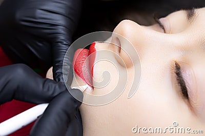Permanent lip tattoo procedure the master prepares the lips for tattooing by outlining the contour with a white pencil Stock Photo