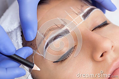 Permanent make-up for eyebrows of beautiful woman with thick brows in beauty salon Stock Photo